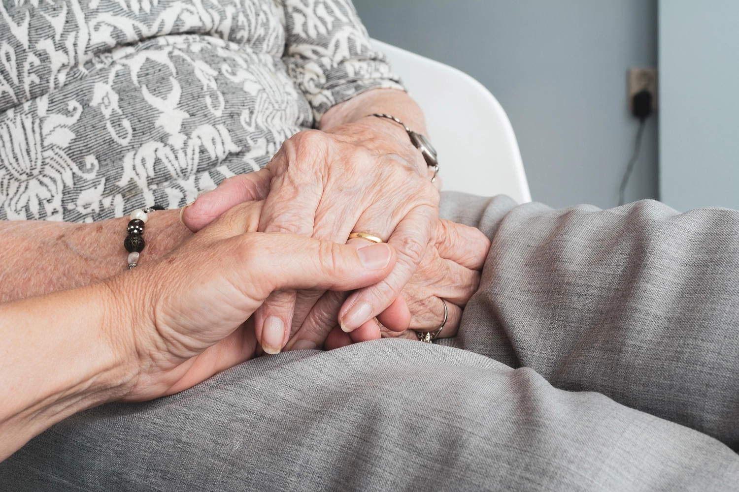 Pflegedienst Döring - Ambulanten Pflegedienstes - Die faltigen Hände einer älteren Person werden in einer unterstützenden Geste sanft von der Hand einer jüngeren Person gehalten.